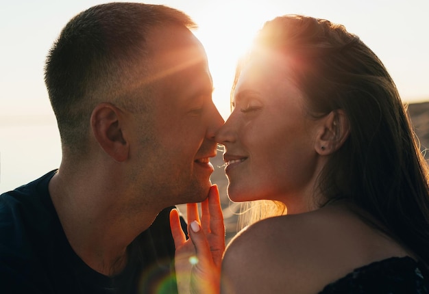 Foto retrato de um homem e uma mulher no momento de beijar ao pôr do sol no verão