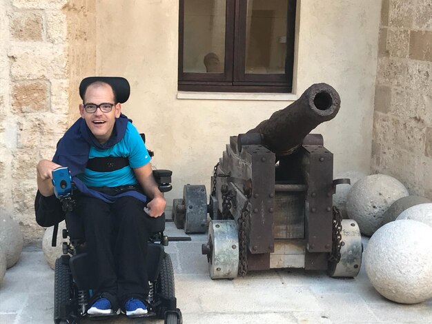 Foto retrato de um homem em cadeira de rodas por um canhão contra um edifício