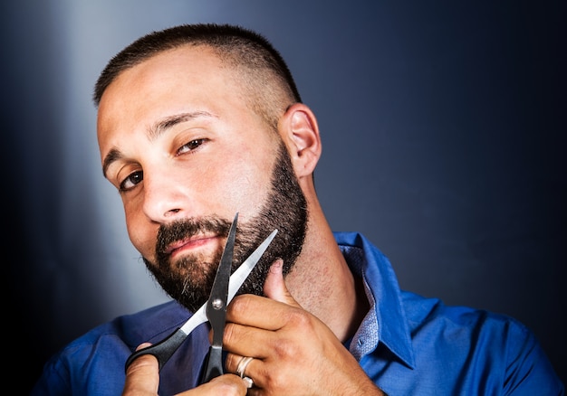 Retrato de um homem enfeitando sua barba com uma tesoura