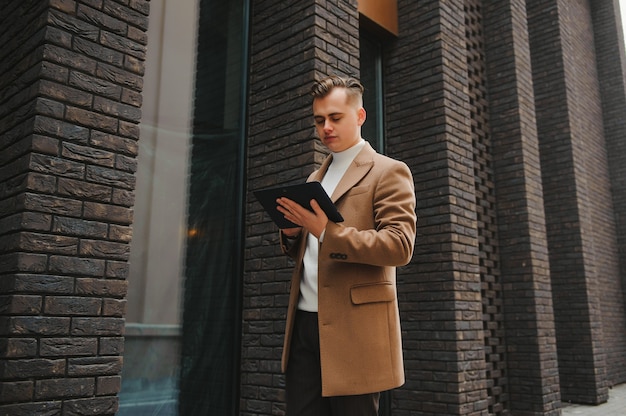 Retrato de um homem estiloso com barba, vestido com um casaco, ao ar livre