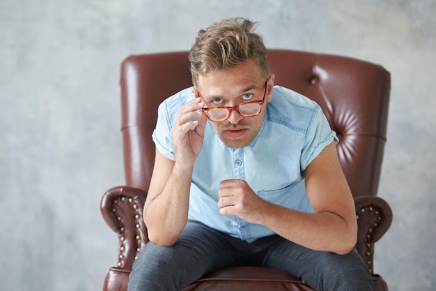 Retrato de um homem estiloso com óculos encara a câmera carismática camisa azul carismática com s