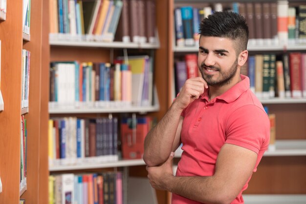 Retrato de um homem estudante universitário na biblioteca Profundidade de campo rasa