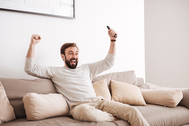 Retrato de um homem excitado segurando o controle remoto