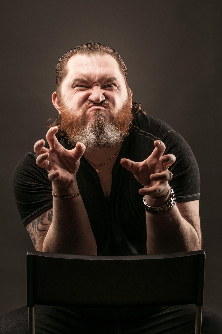 Foto retrato de um homem fazendo uma cara engraçada enquanto estava sentado em uma cadeira contra um fundo preto