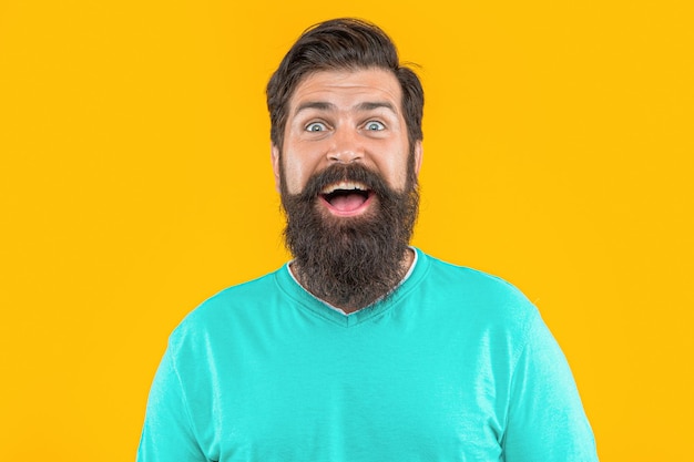 Retrato de um homem feliz e barbudo isolado em fundo amarelo de estúdio