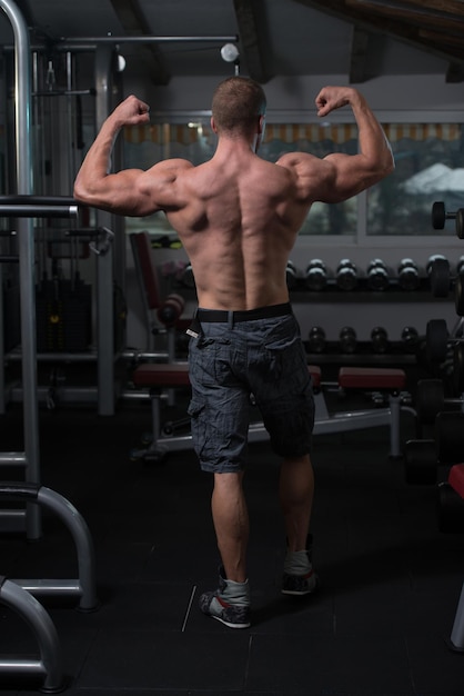 Retrato de um homem fisicamente apto, mostrando seu corpo bem treinado musculoso fisiculturista fitness modelo posando após exercícios