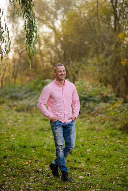 Retrato de um homem forte em jeans e uma camisa rosa.