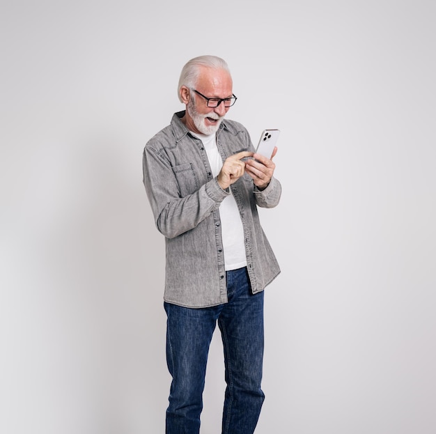 Retrato de um homem freelance sênior alegre rindo e enviando mensagens de texto por smartphone em fundo branco