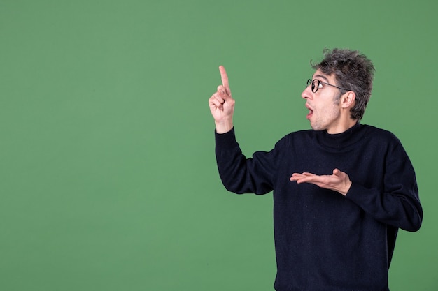 Retrato de um homem gênio vestido casualmente em estúdio, filmado na parede verde