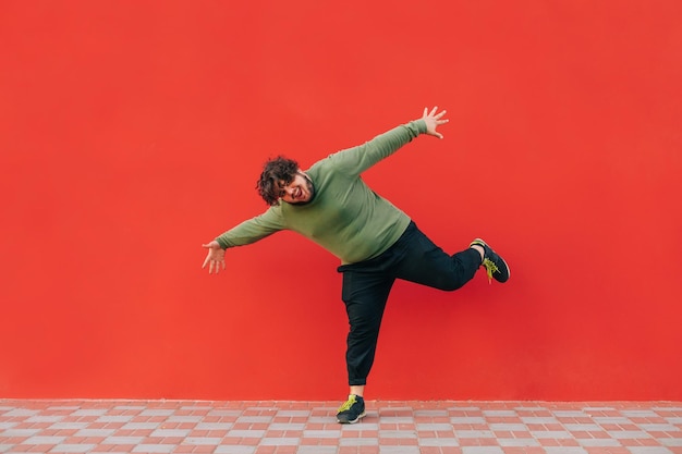 retrato de um homem gordo engraçado dançando em um fundo vermelho vestindo roupas casuais, olhando para a câmera