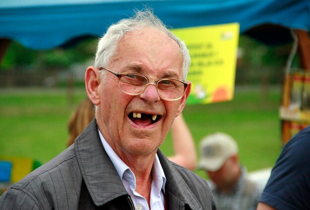 Retrato de um homem idoso com dentes abertos sorrindo enquanto está de pé no parque