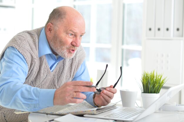 Retrato de um homem idoso com um laptop