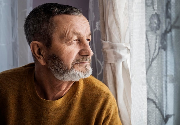 Foto retrato de um homem idoso contra a janela