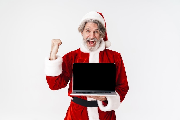 Retrato de um homem idoso de cabelos grisalhos em traje vermelho, segurando um laptop aberto isolado no branco