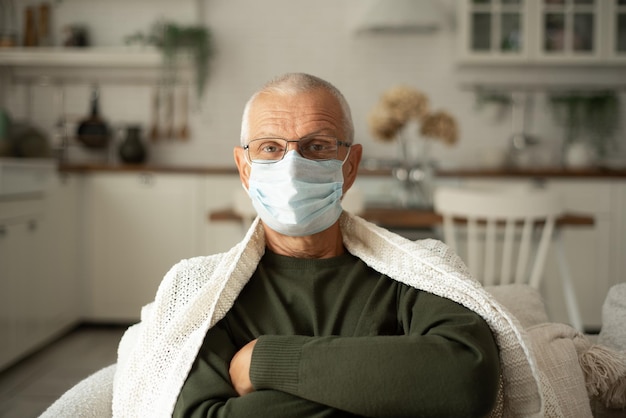 Foto retrato de um homem idoso de cabelos grisalhos em uma máscara protetora em um inverno frio em casa