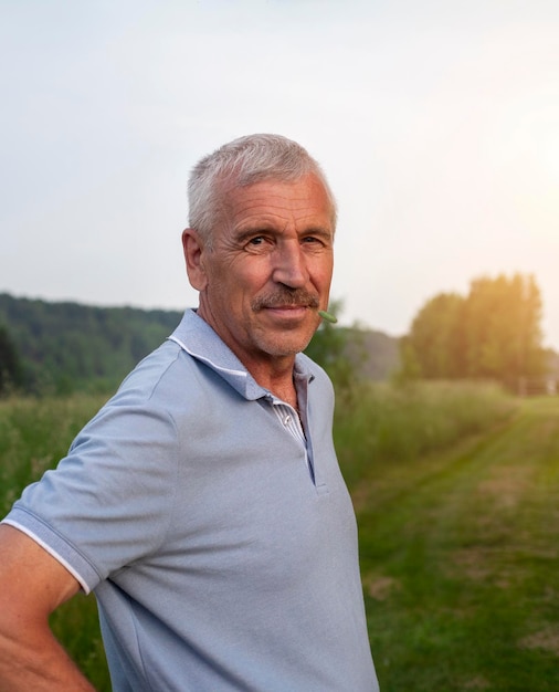 Retrato de um homem idoso de pé em um campo ao pôr-do-sol