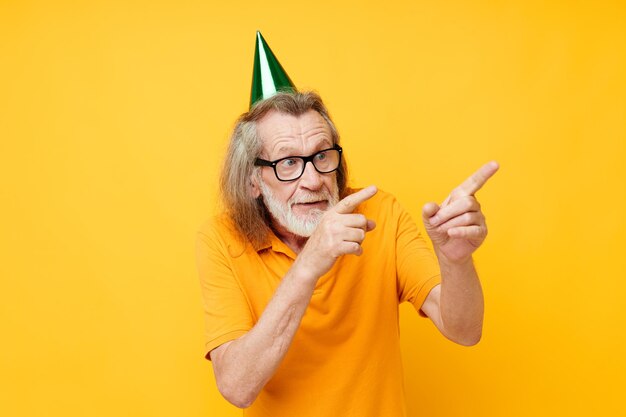 Retrato de um homem idoso em uma camiseta amarela com um boné na cabeça fundo amarelo divertido