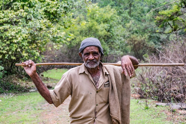 Retrato de um homem idoso segurando um bastão em terra