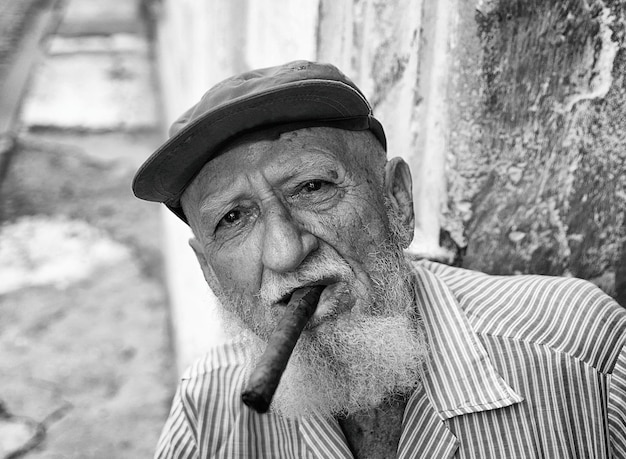 Retrato de um homem idoso usando um chapéu fumando um charuto