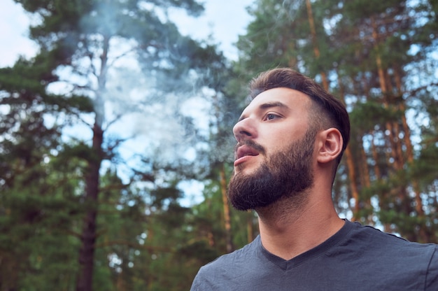 Retrato de um homem jovem e barbudo na natureza ... o conceito de expedição, aventura e vida de acampamento.