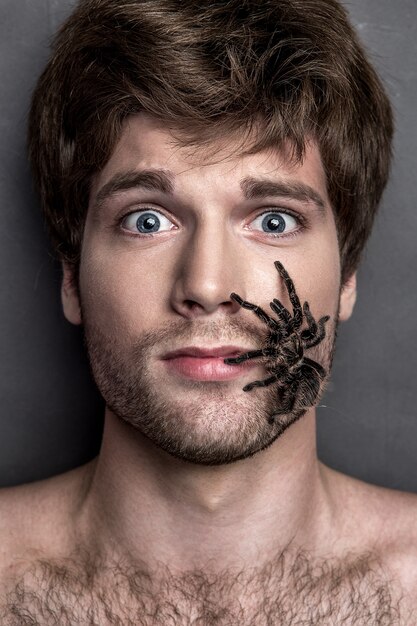 Retrato de um homem jovem e bonito com aranha em seu rosto