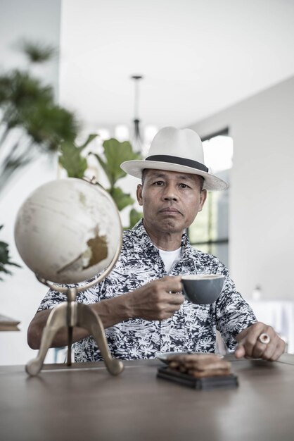 Foto retrato de um homem maduro bebendo enquanto está sentado à mesa