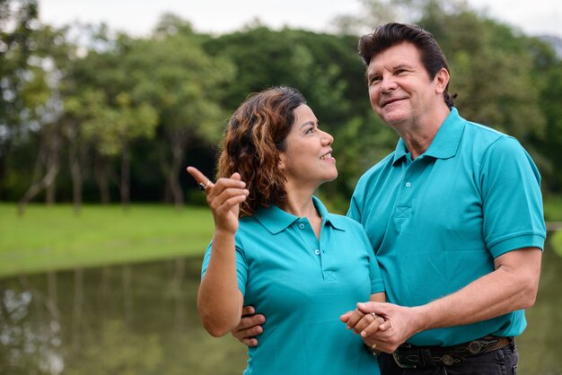 Retrato de um homem maduro e uma mulher asiática madura como um casal multiétnico, juntos e apaixonados no parque ao ar livre