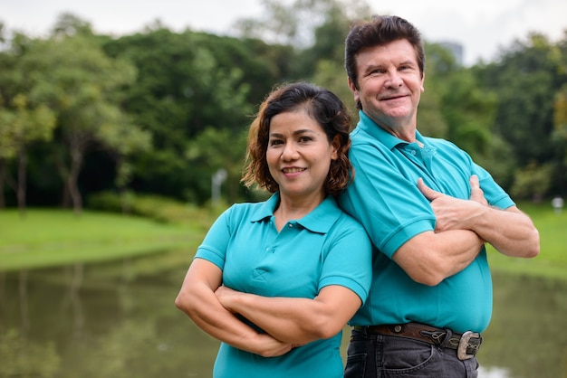 Retrato de um homem maduro e uma mulher asiática madura como um casal multiétnico, juntos e apaixonados no parque ao ar livre