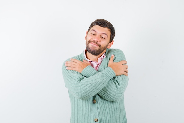 Retrato de um homem maduro se abraçando com uma camisa, um casaco de lã e olhando para a frente alegre