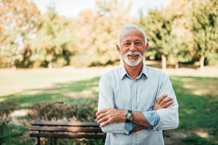 Retrato de um homem mais velho sorridente no parque.