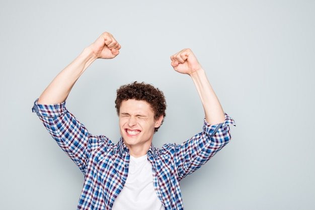 Retrato de um homem moreno feliz vestindo roupas casuais levantando os punhos celebrando