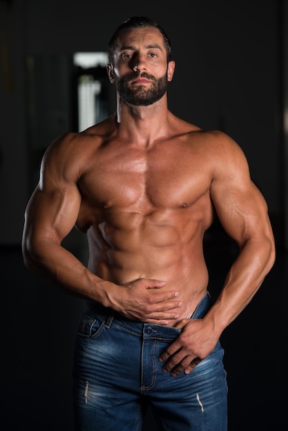 Retrato de um homem musculoso sexy em calças posando após o exercício no ginásio
