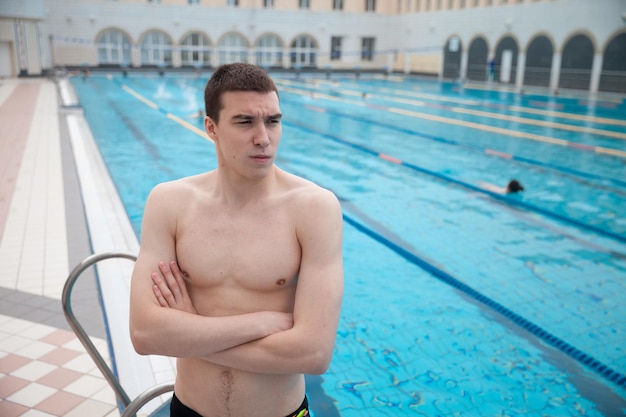 Retrato de um homem nadador em forma na piscina olhando para a câmera Retrato de um nadador masculino competitivo perto da piscina