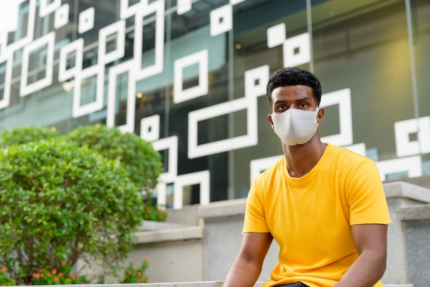 Retrato de um homem negro africano bonito vestindo uma camiseta amarela ao ar livre na cidade de bangkok, tailândia