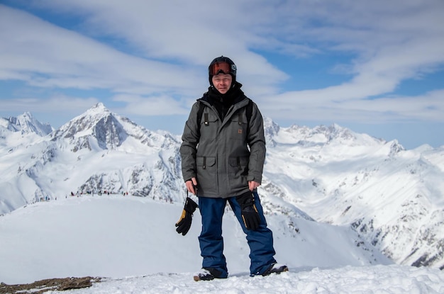 Retrato de um homem no topo de uma montanha nevada.