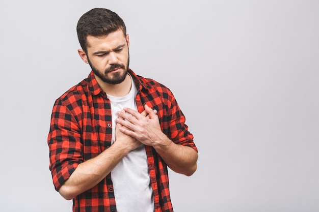 Retrato de um homem ocasional novo que está isolado sobre o fundo branco, tendo um ataque cardíaco. mágoa.