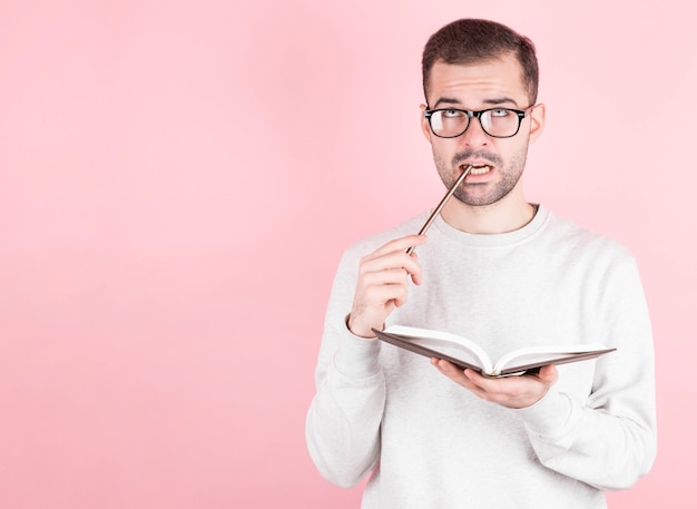 Retrato de um homem pensativo com um caderno e um lápis na boca.