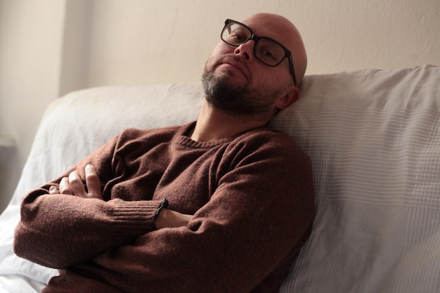 Retrato de um homem pensativo relaxando na cama em casa