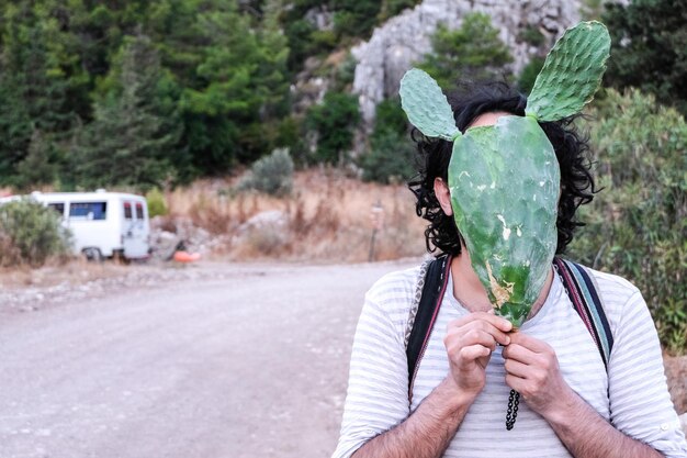 Foto retrato de um homem segurando uma planta de cacto na estrada