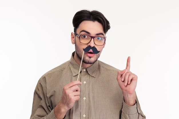 Retrato de um homem segurando uma vara com bigode e apontando o dedo isolado em uma parede branca