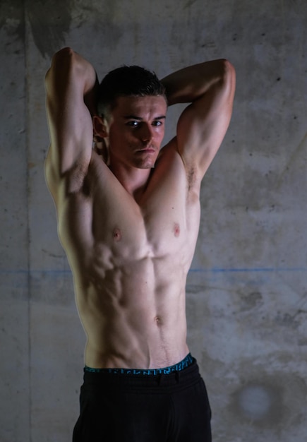 Retrato de um homem sem camisa de pé contra a parede