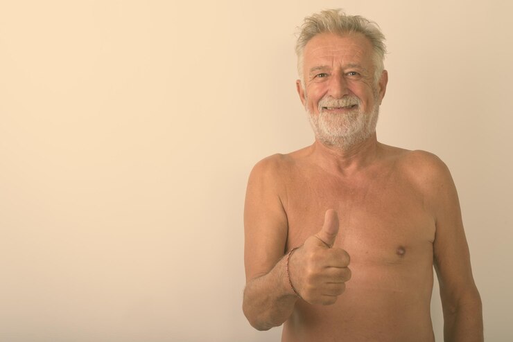 Foto retrato de um homem sem camisa de pé contra um fundo cinzento
