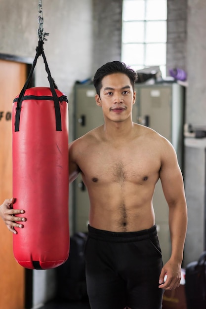 Retrato de um homem sem camisa de pé no saco de boxe