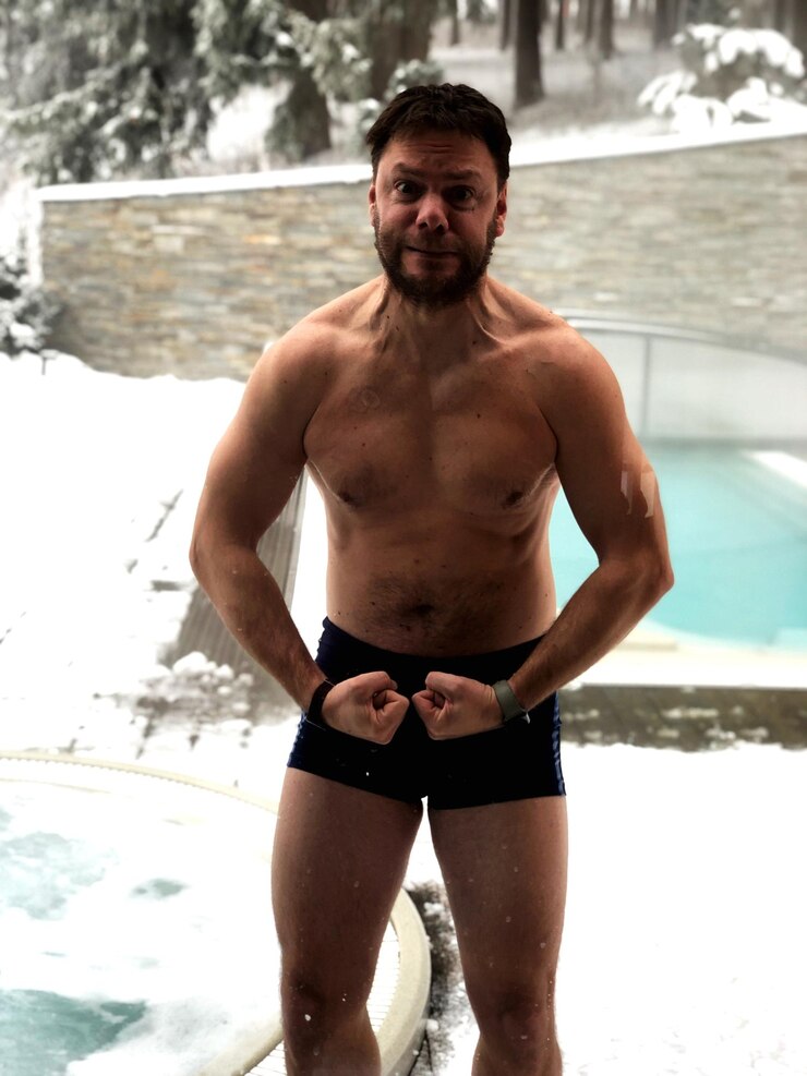 Foto retrato de um homem sem camisa flexionando os músculos enquanto está de pé contra a piscina