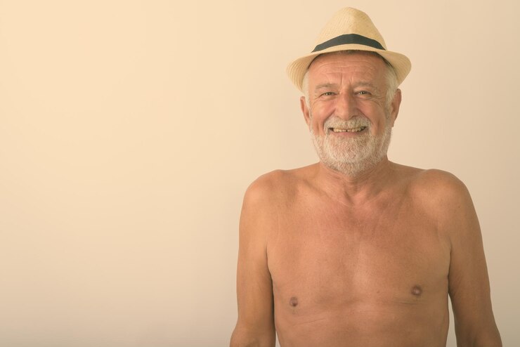 Foto retrato de um homem sem camisa usando um chapéu contra um fundo cinzento