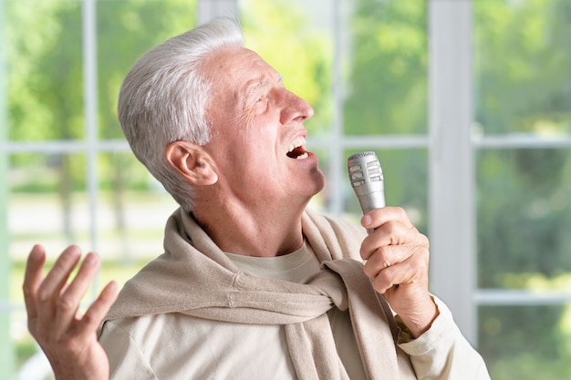 Retrato de um homem sênior cantando no microfone