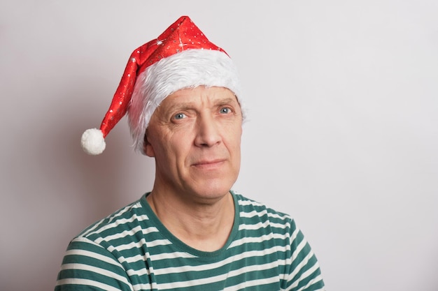 Retrato de um homem sênior com chapéu de Papai Noel em um espaço de cópia de fundo branco