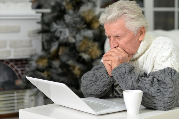 Retrato de um homem sênior com laptop em casa