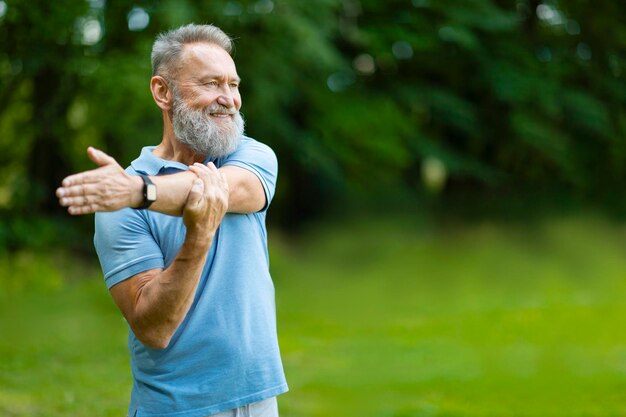 Retrato de um homem sênior feliz treinando ao ar livre esticando os músculos do braço