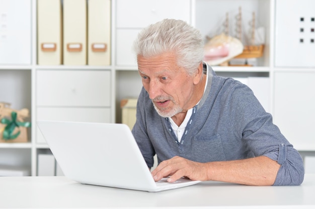 Retrato de um homem sênior usando laptop em casa